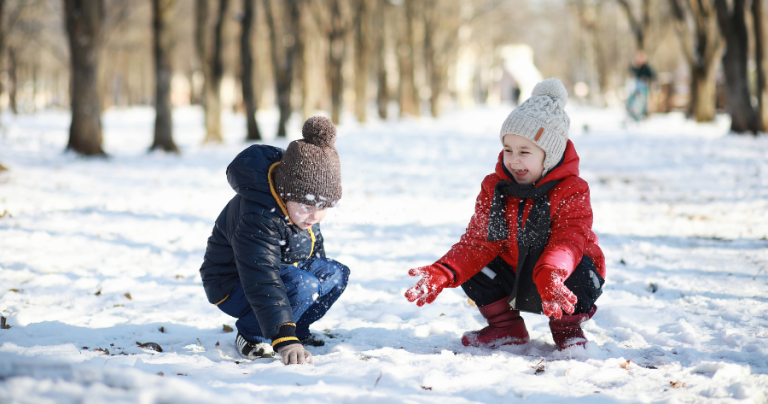 two kids playing in the snow in the winter