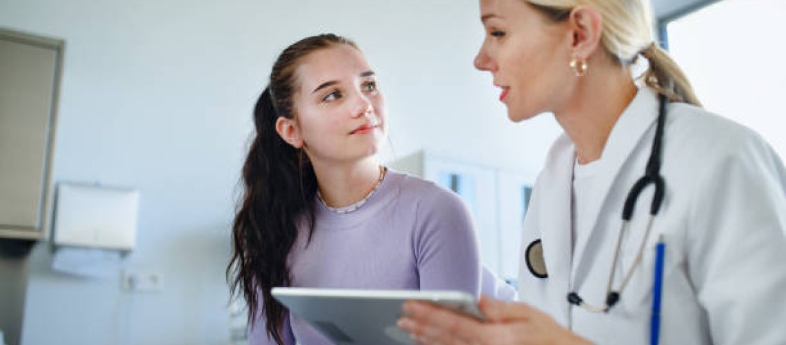 Young woman doctor explaining diagnosis to teenage girl in her ambulance office.
